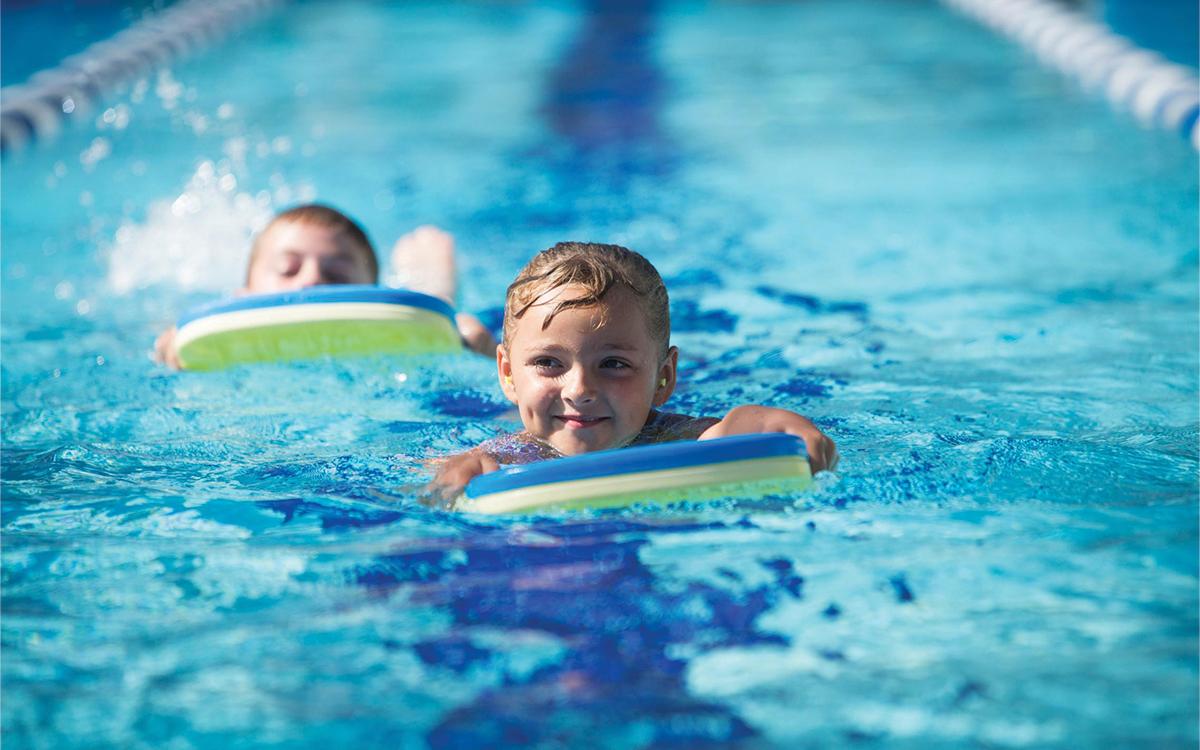 smiling girl in pool on kickboard