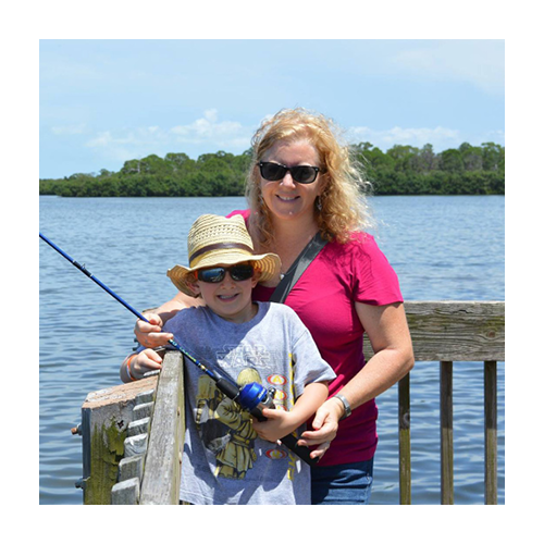 Mother and kid on the dock holding fishing rod together, wearing sunglasses. Sunny day, blue water, mangrove trees in the background