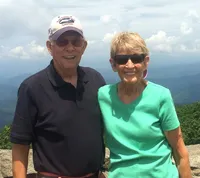 senior man and woman pose for a photo with a mountain background