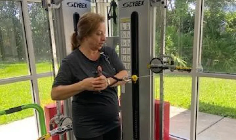 A participant in the Moffitt Cancer Survivorship works out, demonstrating a standing cable oblique twist.
