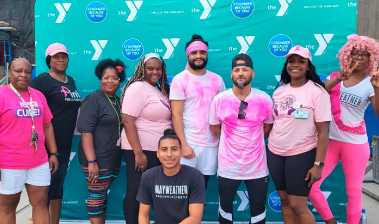 9 men and women standing in front of a YMCA logo backdrop