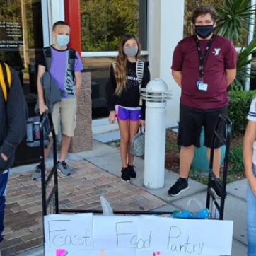 Middle school kids wearing masks collecting food