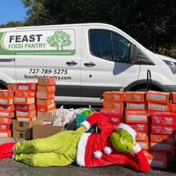 food distribution and the grinch laying on ground in front of boxes of food