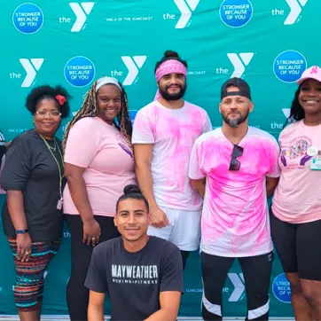 9 men and women standing in front of a YMCA logo backdrop